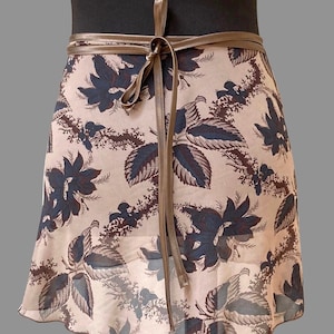 May include: A beige wrap skirt with a brown leather tie and a floral print featuring dark blue and brown leaves.