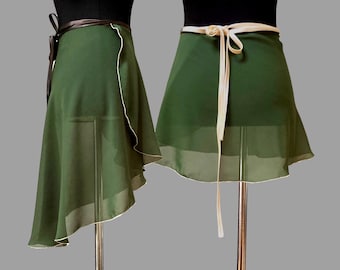 May include: Two green wrap skirts. One has a brown tie, the other has a cream-colored tie. Both skirts are made of a sheer fabric with a white trim along the edges. The skirts are displayed on mannequins against a gray background.