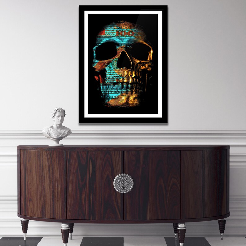 May include: A framed print of a skull with a gold and blue design. The skull is made up of dollar bills, with the number "100" visible on the forehead.