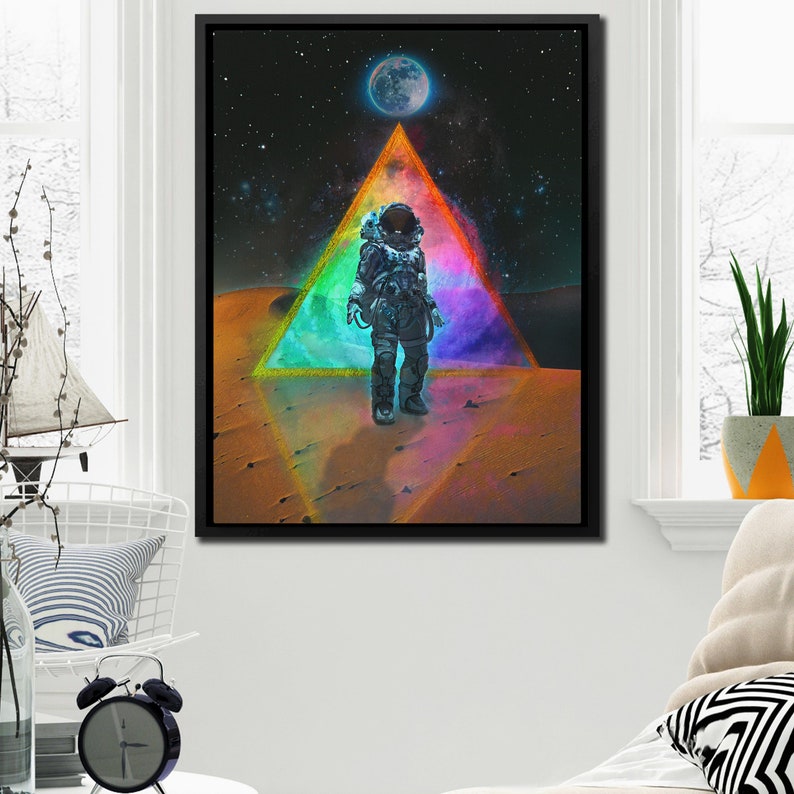Op de afbeelding: Een astronaut in een ruimtepak staat op een rood, oranje en geel woestijnlandschap. Een grote, kleurrijke driehoek omringt de astronaut, met een blauwe maan op de achtergrond.