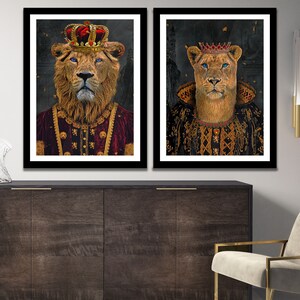 May include: Two framed portraits of a lion and lioness wearing crowns and royal robes. The lion is wearing a red robe with gold trim and the lioness is wearing a black robe with gold trim. Both portraits have a dark background.