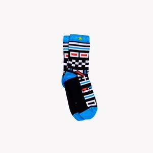 May include: A pair of black socks with a geometric design. The socks feature a blue toe and cuff, with a pattern of white, red, and black squares and rectangles. The top of the sock has the text "POP AFRI" in white.
