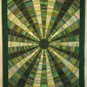 May include: A green and white quilt with a circular design. The quilt is made of many different fabrics and is stitched together in a radial pattern. The center of the quilt is a dark green circle.