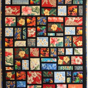 May include: A colorful quilt with a black border, featuring rectangular blocks of various floral and tropical patterns. The quilt showcases vibrant red, yellow, blue, and orange hues, with images of hibiscus flowers, palm trees, and other tropical foliage.