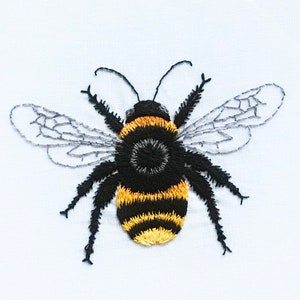 Puede incluir: Abeja bordada con rayas negras y amarillas y alas grises sobre un fondo blanco.