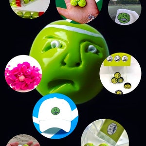 May include: A collection of green tennis balls with different facial expressions. Some balls are in a clear plastic container, others are in a hand, and some are on a white surface. There is also a white baseball cap with a green face on it.