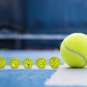 May include: A row of yellow tennis balls with different facial expressions, lined up on a blue tennis court. A single yellow tennis ball is in the foreground, slightly out of focus.