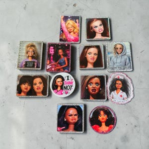 Puede incluir: Una colección de pines rectangulares y circulares con purpurina que muestran varios rostros de muñecas con expresiones gruñonas o escépticas. Algunos pines incluyen texto como Not Today Babe, I Think Not, Living The Dream e IDK, I just work here.