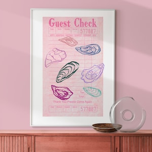 Puede incluir: Impresión enmarcada con un diseño de recibo rosa y ilustraciones de ostras coloridas. El texto "Guest Check" está en la parte superior y "Thank You-Please Come Again" en la parte inferior. La obra de arte se exhibe en una pared rosa.
