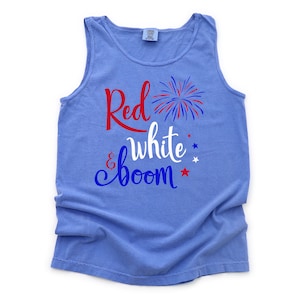 Puede incluir: Una camiseta sin mangas azul con el texto "Red & white boom" en letras rojas, blancas y azules. Un gr&aacute;fico de fuegos artificiales rojo, blanco y azul est&aacute; al lado de la palabra "Red".
