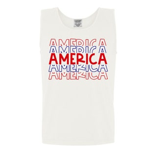May include: White tank top with a red, white, and blue graphic that says "AMERICA" five times.
