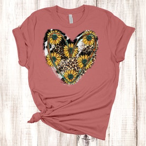 May include: A mauve t-shirt with a heart-shaped design featuring sunflowers, leopard print, and turquoise accents.