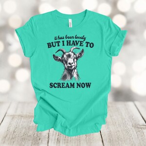 May include: A turquoise t-shirt with a black and white illustration of a goat and the text "it has been lovely BUT I HAVE TO SCREAM NOW".