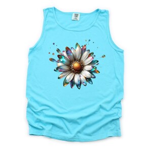 May include: A turquoise tank top with a colorful, metallic daisy graphic. The daisy has a white center and iridescent petals.