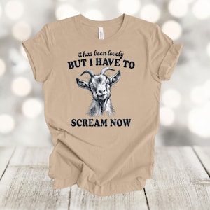 May include: A tan t-shirt with a black and white goat illustration and the text "it has been lovely BUT I HAVE TO SCREAM NOW".