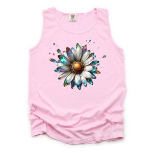 May include: Pink sleeveless tank top with a colorful, iridescent daisy graphic. The daisy has a white center and blue, green, and gold petals.