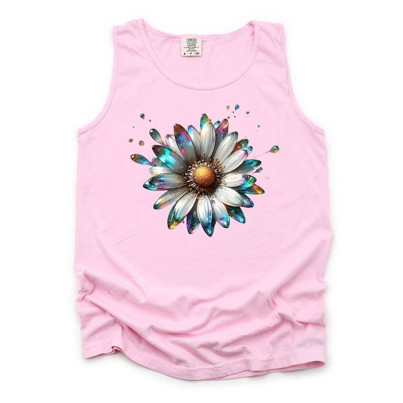 May include: Pink sleeveless tank top with a colorful, iridescent daisy graphic. The daisy has a white center and blue, green, and gold petals.