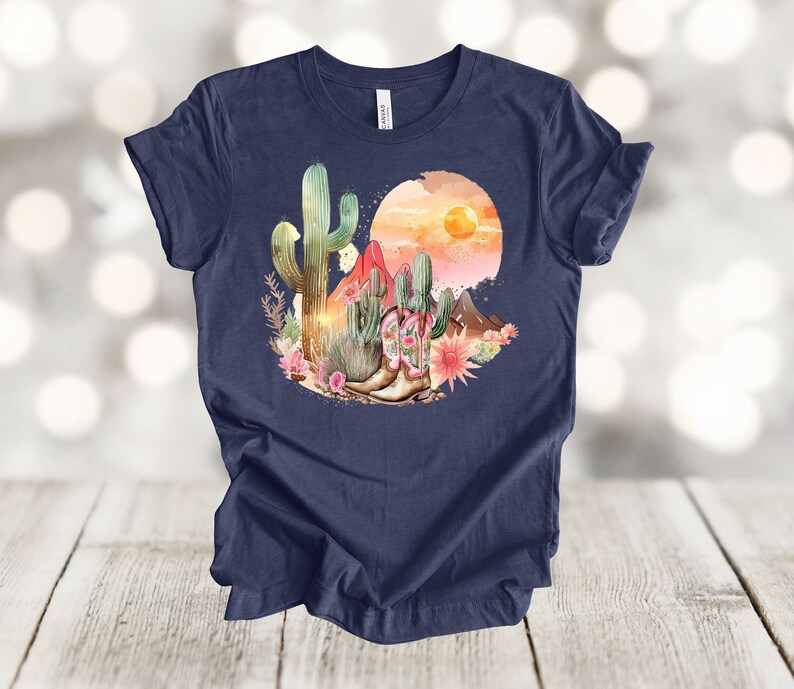 Camiseta gráfica Atardecer en el desierto: Camiseta estilo vaquero con estampado de cactus y botas. Heather Navy