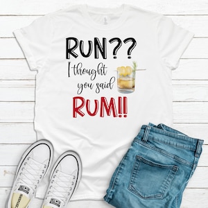 May include: White t-shirt with black text that reads "RUN?? I thought you said RUM!" and a drawing of a glass of rum with a lemon wedge and a sprig of rosemary.