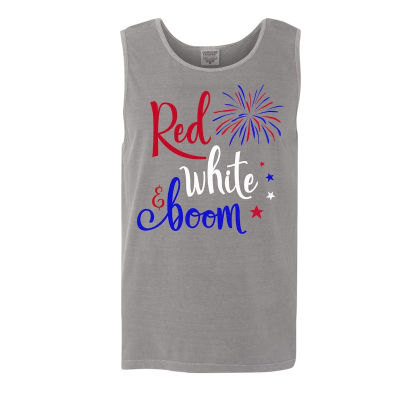 Puede incluir: Una camiseta sin mangas gris con el texto "Red, White & Boom" en letras rojas, blancas y azules. Un gr&aacute;fico de fuegos artificiales rojo, blanco y azul est&aacute; al lado del texto.