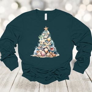 May include: A teal long-sleeved shirt with a watercolor design of a Christmas tree made of seashells and starfish.
