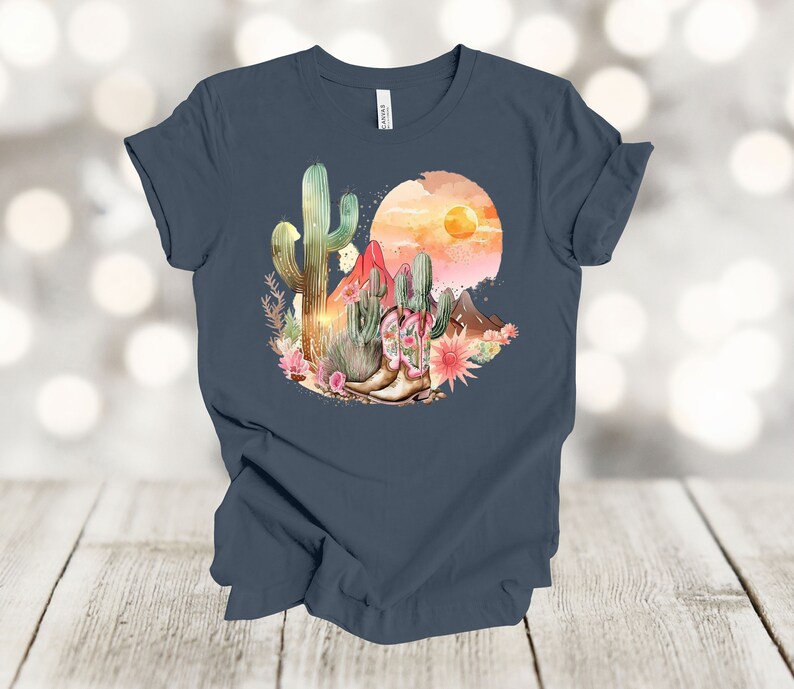 Camiseta gráfica Atardecer en el desierto: Camiseta estilo vaquero con estampado de cactus y botas. Vintage Navy