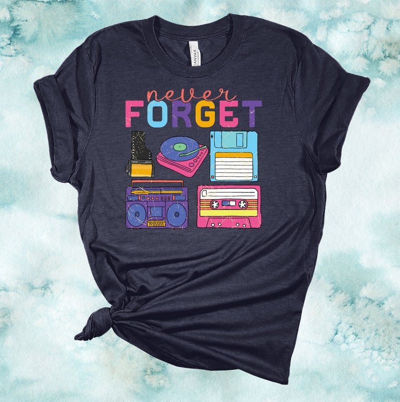 May include: A navy blue t-shirt with the text "never FORGET" in rainbow colours. The shirt features a graphic of vintage technology, including a cassette tape, a floppy disk, a record player, and a boombox.