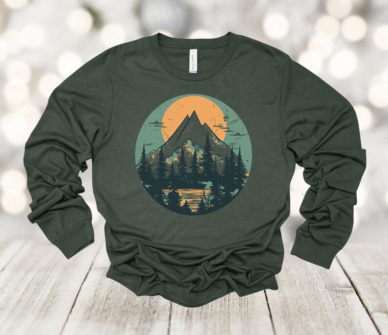 May include: A dark green long-sleeved t-shirt with a vintage-style graphic of a mountain range with a sunset behind it. The graphic is in a circle with a light blue background.