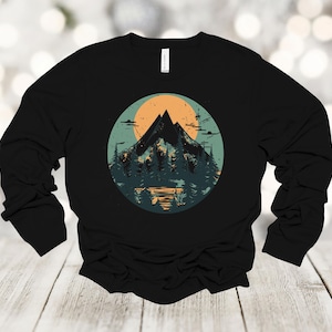 May include: Black long-sleeve shirt with a graphic print of a mountain range and a sunset in a circle.