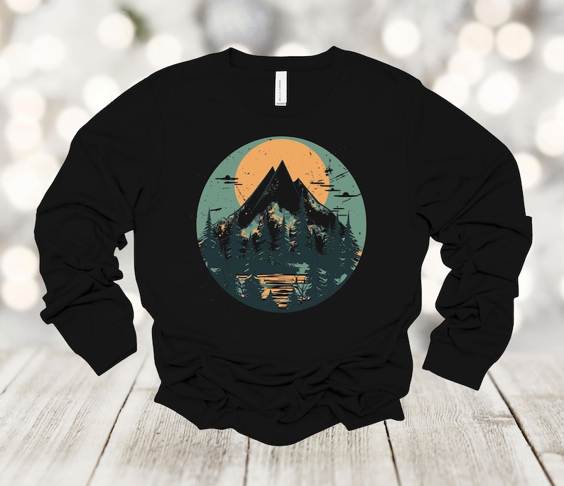 May include: Black long-sleeve shirt with a graphic print of a mountain range and a sunset in a circle.