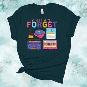 May include: A teal blue t-shirt with the text "never FORGET" in rainbow colours. The shirt features a graphic of vintage technology items, including a cassette tape, a floppy disk, a record player, a boombox, and a camera.