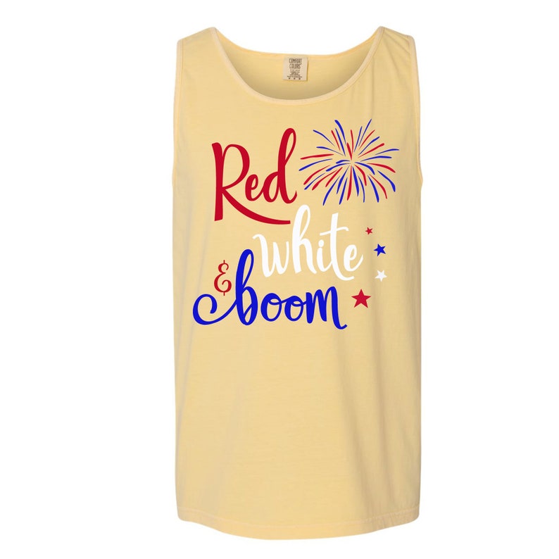 Puede incluir: Una camiseta sin mangas amarilla con el texto "Red & White Boom" en letras rojas, blancas y azules. Un gr&aacute;fico de fuegos artificiales rojo, blanco y azul est&aacute; al lado del texto.