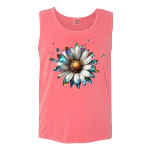May include: A coral pink sleeveless tank top with a white daisy graphic. The daisy has iridescent blue and green petals and a gold center.