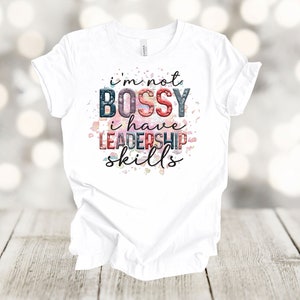 May include: White t-shirt with a graphic print that says "I'm not bossy I have leadership skills". The graphic is in a colorful watercolor style.