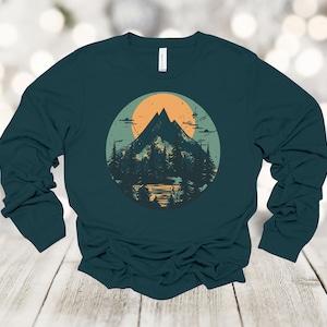May include: A teal long-sleeve shirt with a graphic of a mountain range and a sun in a circle. The mountains are green and brown, and the sun is orange.