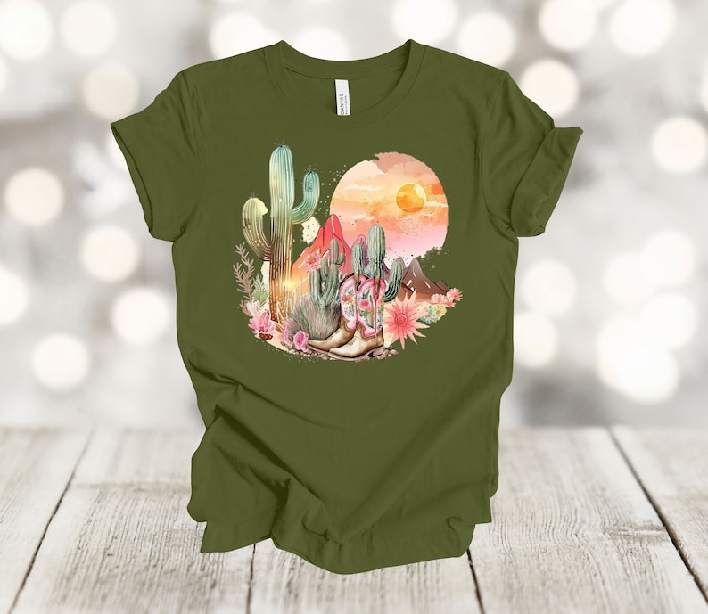 Camiseta gráfica Atardecer en el desierto: Camiseta estilo vaquero con estampado de cactus y botas. Olive