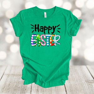 May include: A green t-shirt with the text "Happy Easter" in black lettering. The word "Easter" is decorated with colorful stripes, polka dots, and zigzags.
