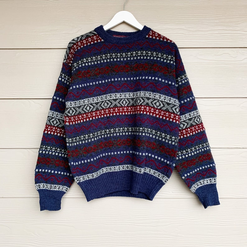 May include: A blue, red, white, and gray patterned sweater with long sleeves.