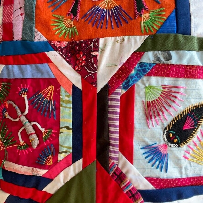 May include: A colorful patchwork quilt with various fabrics and embroidered designs. The quilt features a red, blue, and green color scheme with intricate stitching and patterns. The quilt is made up of different squares and triangles, each with a unique design.