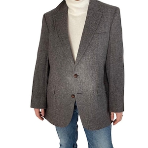 May include: A gray herringbone blazer with a two-button closure. The blazer has a classic fit and a slightly longer length.
