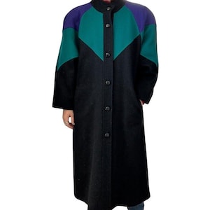 May include: A long black wool coat with a green and purple color block design. The coat has a button-up front and a stand-up collar.