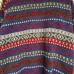May include: A blue, red, white, and gray patterned sweater with a fair isle design.