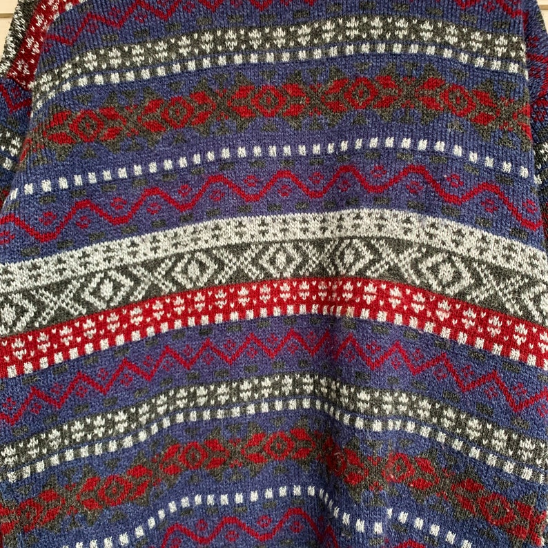 May include: A blue, red, white, and gray patterned sweater with a fair isle design.