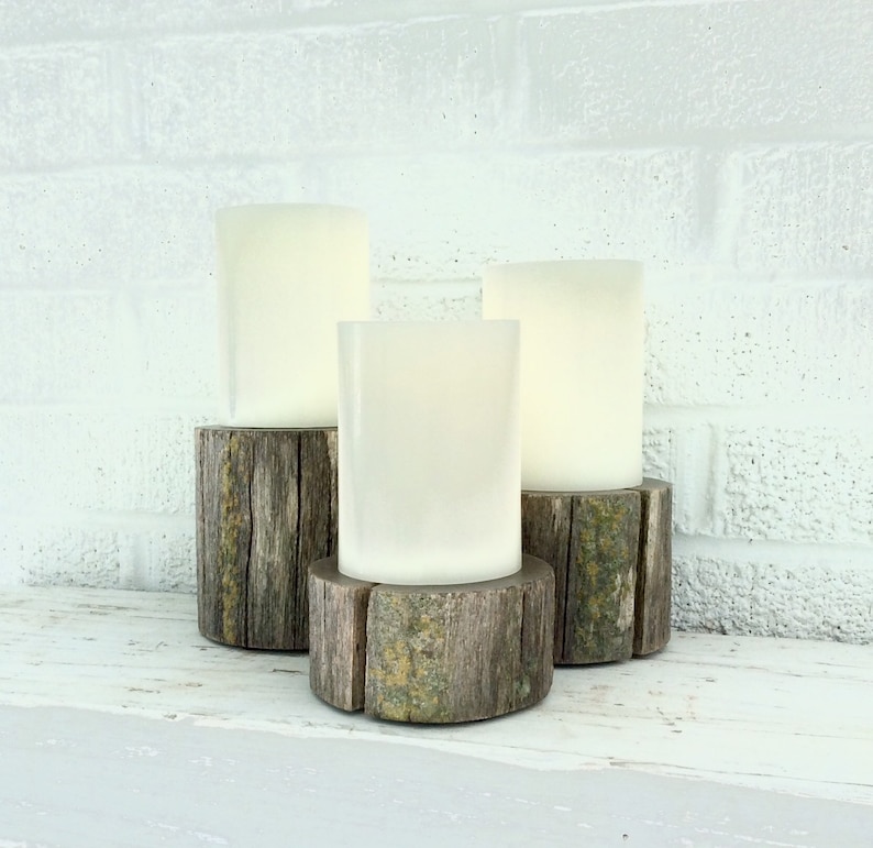 Peut inclure: Trois bougies blanches en forme de pilier sur des bases en bois rustiques. Les bougies sont dispos&eacute;es en forme de triangle. Les bases sont en bois vieilli avec une finition naturelle.