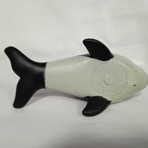 K&ouml;nnte beinhalten: Ein schwarzes und wei&szlig;es Plastikspielzeug-Orca-Wal. Der Wal liegt auf der Seite mit dem Schwanz in der Luft.