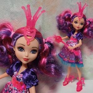 K&ouml;nnte beinhalten: Zwei Modepuppen mit pinken und lila Haaren, die lila und rosa Kleider und pinkfarbene Accessoires tragen. Die Puppen haben blaue Augen und posieren vor einem hellen Hintergrund. Eine Puppe ist im Vordergrund, die andere im Hintergrund.