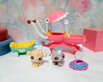 Pode incluir: Um carrinho de brinquedo rosa com uma alça branca e um guarda-sol rosa. Também estão presentes dois animais de brinquedo e uma pequena carroça verde com interior amarelo. Um bloco rosa e um acessório roxo e azul também estão na imagem.