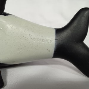 K&ouml;nnte beinhalten: Schwarz-wei&szlig;es Plastikspielzeug-Orca mit wei&szlig;em Bauch und schwarzem R&uuml;cken und Schwanz. Das Spielzeug hat ein Copyright-Symbol und den Schriftzug "DISNEY" auf der Seite.