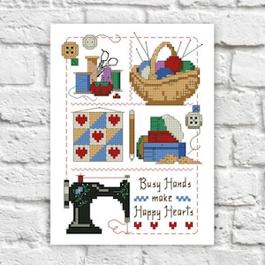 Op de afbeelding: Een kruissteekpatroon met een naaimachine, een mand met garen, een quiltblok en een stapel stof. De tekst "Busy Hands make Happy Hearts" is in het ontwerp opgenomen.