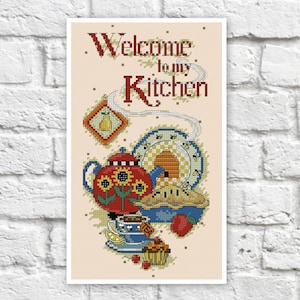 May include: Cross-stitch pattern featuring a teapot, pie, and beehive with the text "Welcome to my Kitchen".